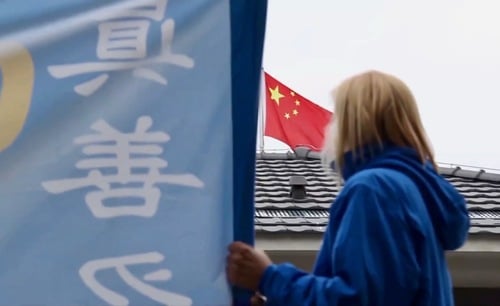 Una praticante serba del Falun Gong tiene uno striscione davanti all'ambasciata cinese a Belgrado (Minghui.org, 2019)