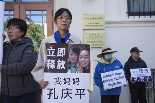 La signora Liu Zhitong tiene in mano una foto di sua madre. La scritta dice: "Liberate immediatamente mia madre Kong Qingping". (Minghui.org)